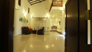 A spacious lobby with a polished floor, a sofa set, a dining area, and a staircase leading to an upper level. - Sethum Villa - Unawatuna (Koggala)