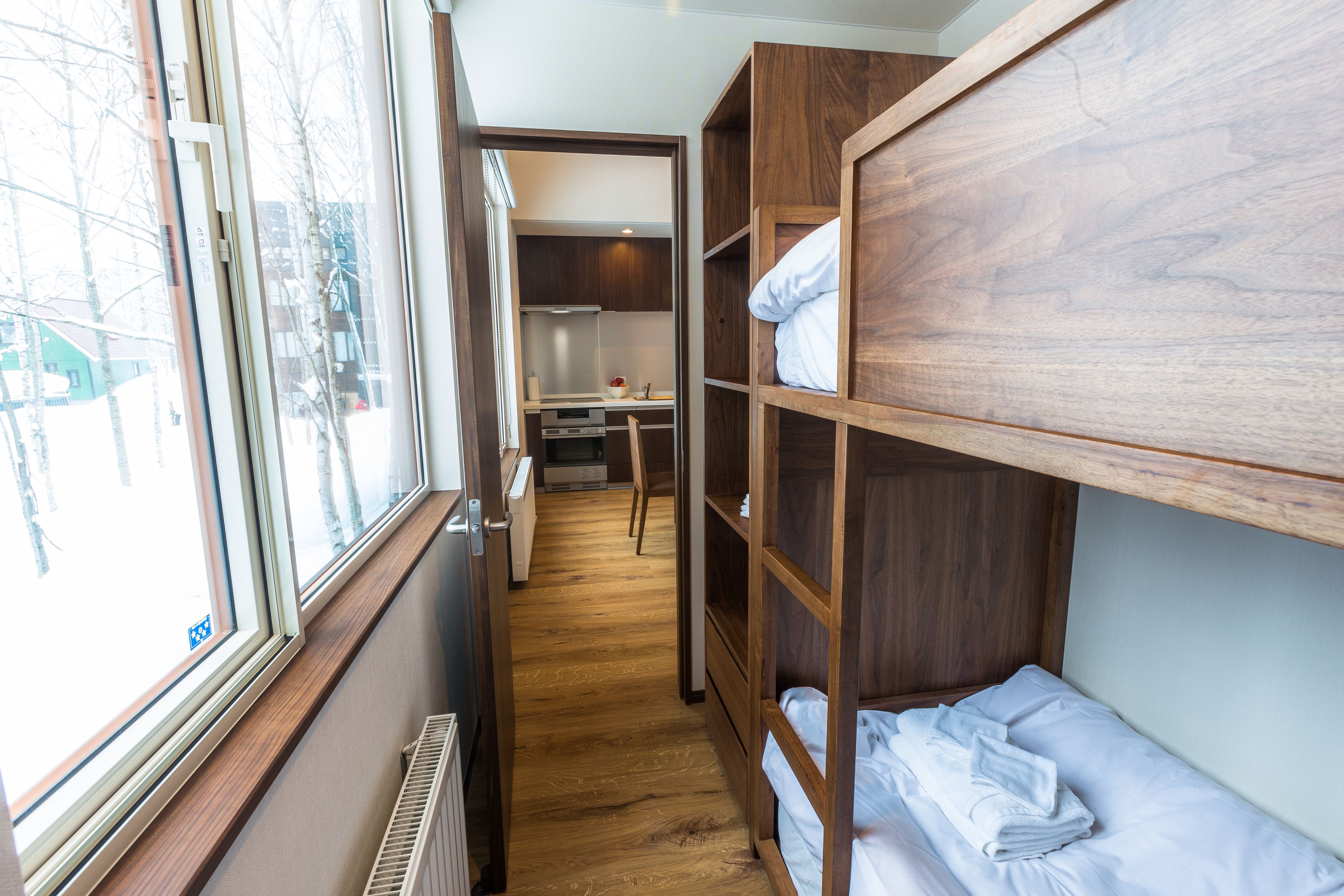 A narrow hallway with bunk beds on one side and a kitchenette area on the other.