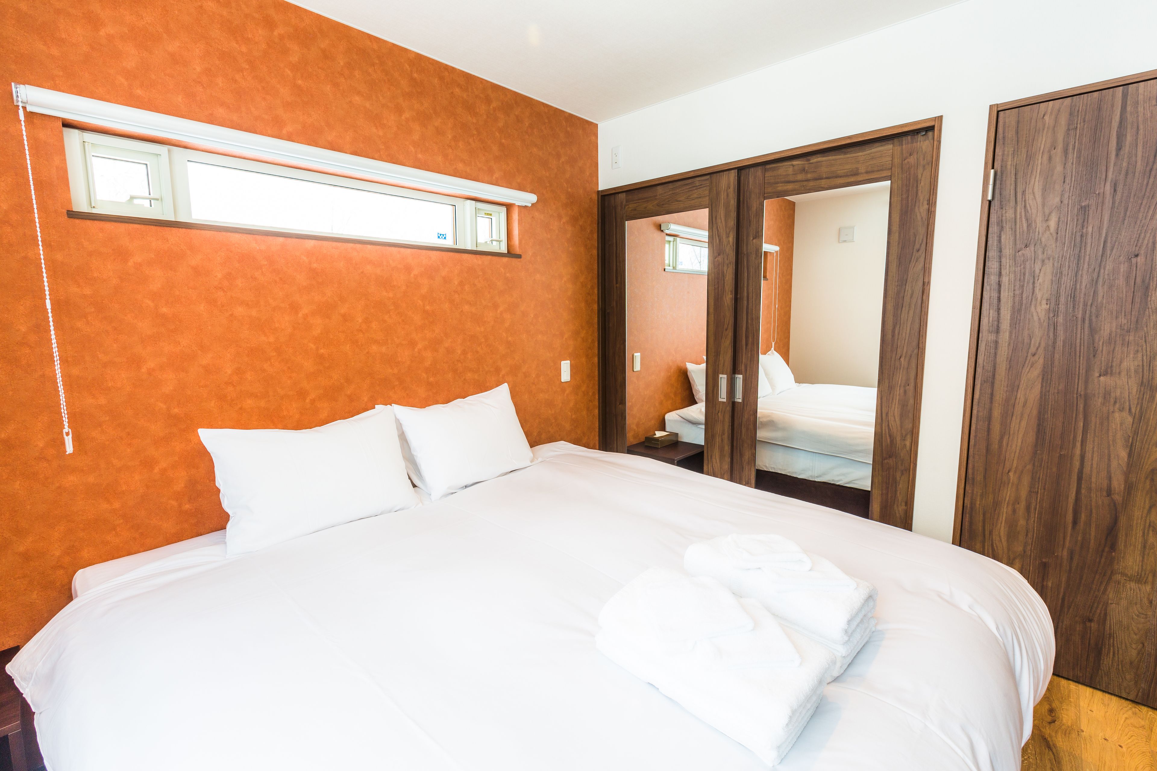 A hotel room with a large bed, a wooden wardrobe, and a mirror.
