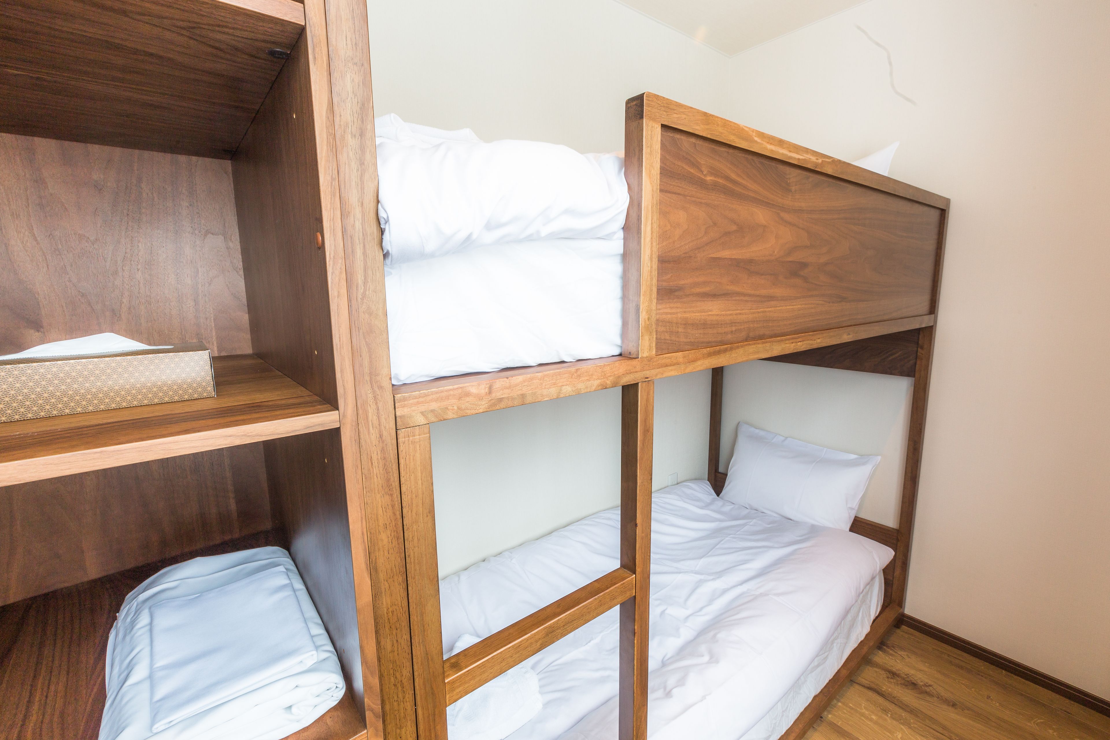 Un letto a castello con struttura in legno e biancheria bianca.