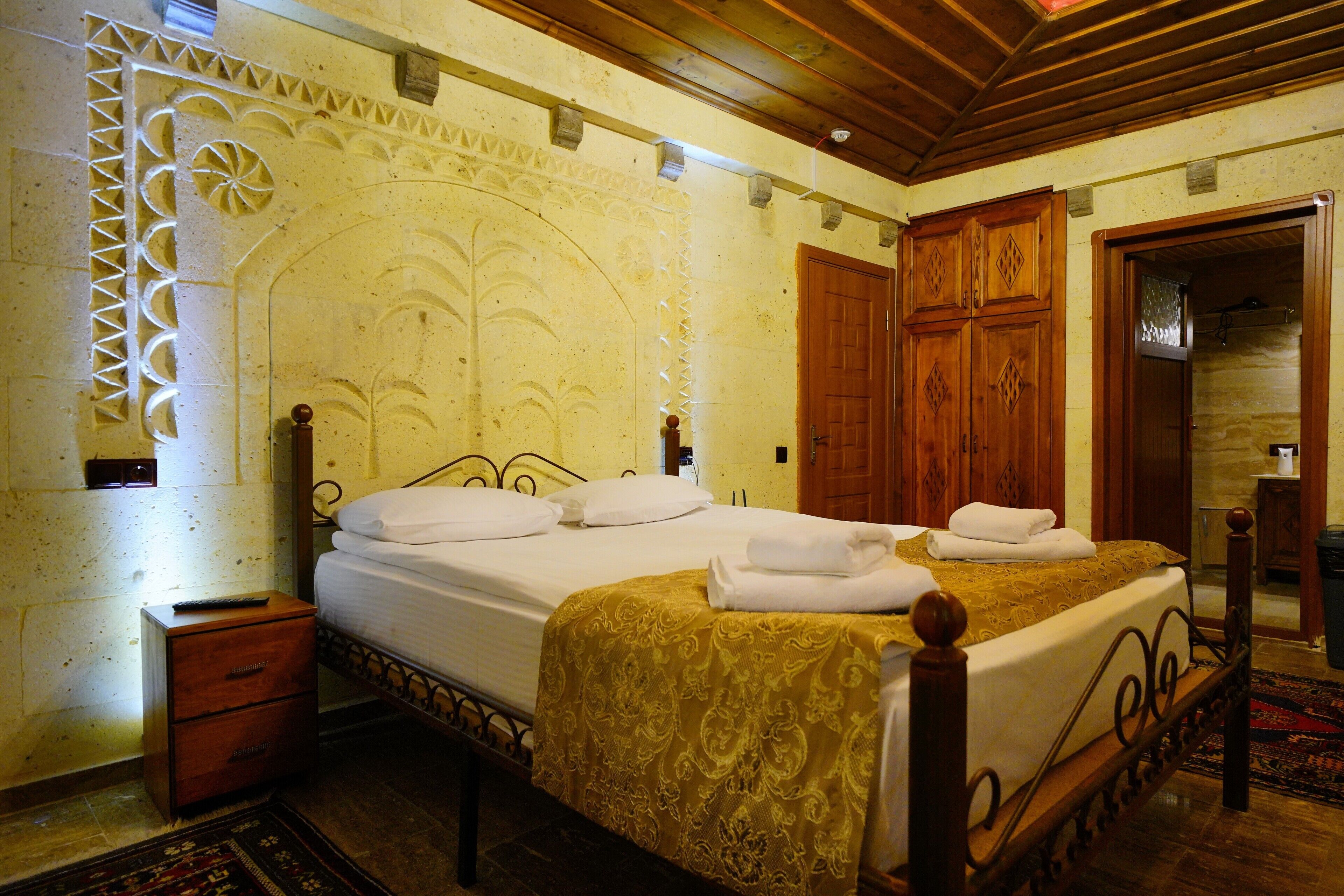 A bedroom with a bed, wooden wardrobe, and a nightstand.
