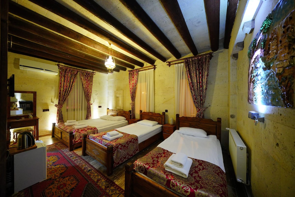 Una habitación tradicional con dos camas de madera, un radiador y techo de madera.