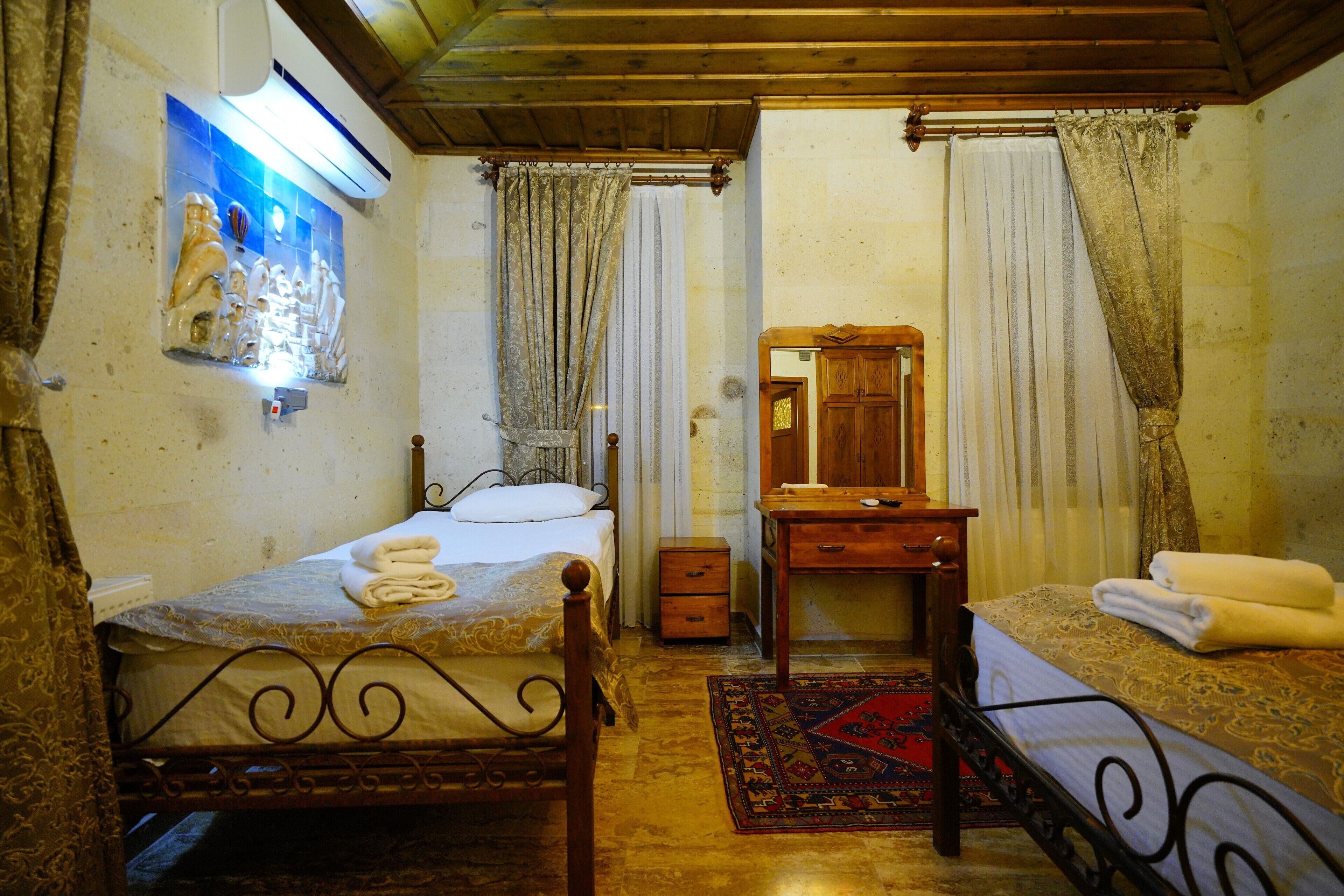 A bedroom with two beds, a wooden dresser, a mirror, and a wall-mounted air conditioner.