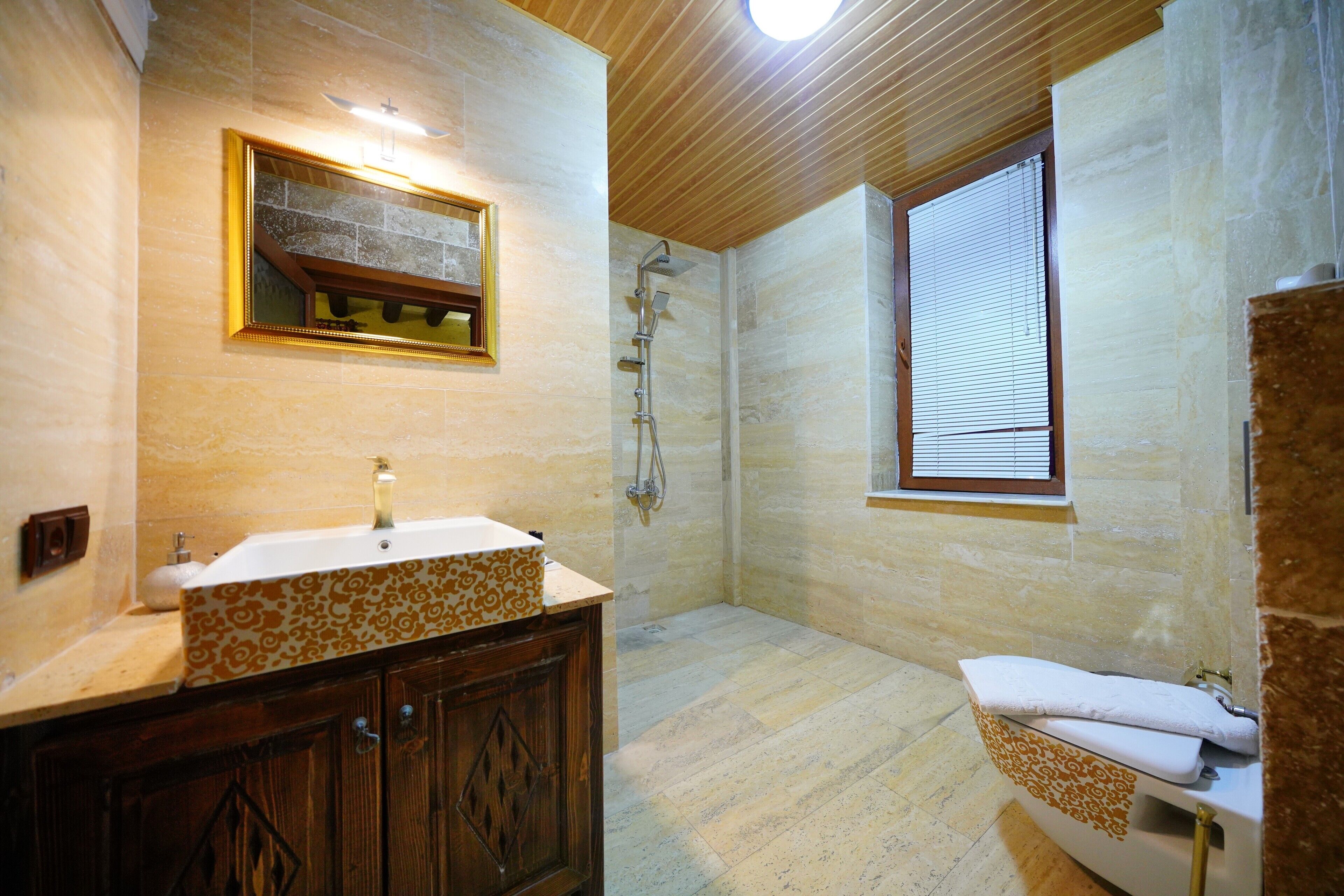 Un baño con tocador de madera, ducha y ventana.