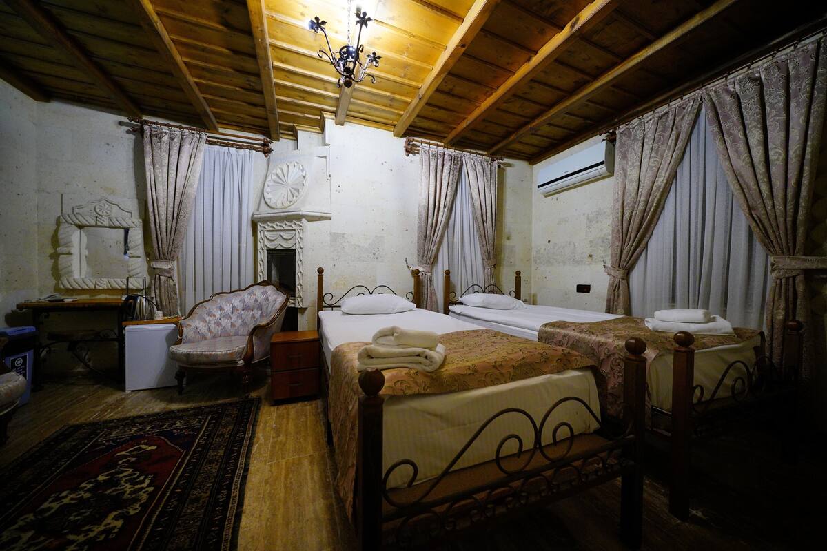 Una habitación tradicional con dos camas, techo de madera y una araña.
