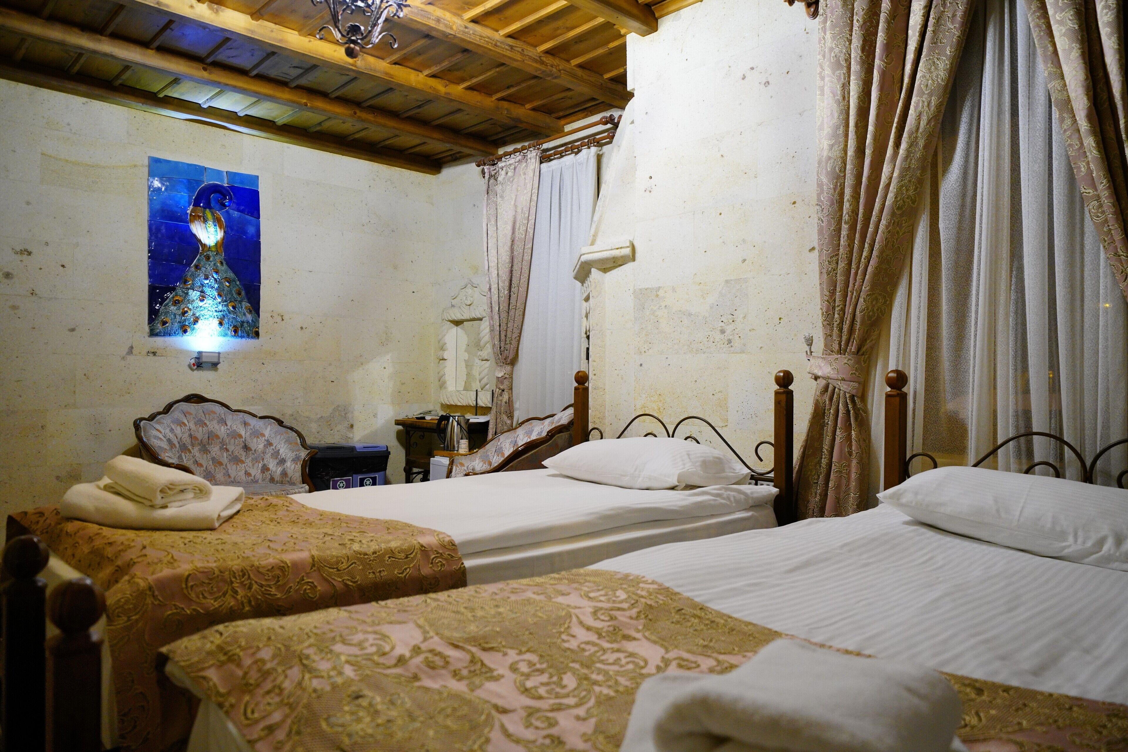 Una habitación con dos camas, techo de madera, lámpara de pared y un cuadro decorativo.