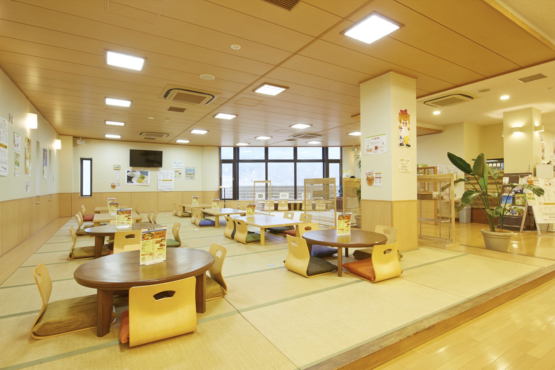 Un vaste espace dédié à la salle à manger, avec de nombreuses tables et chaises, de grandes fenêtres et une vue sur la ville.
