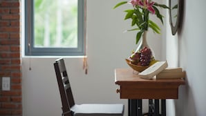 A wooden table with a vase of flowers, a bowl of fruit, and a book.