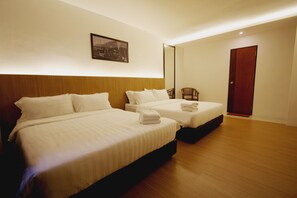 Une chambre d’hôtel avec deux lits, une tête de lit en bois, une chaise et une porte.