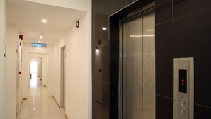 A modern elevator with a digital display showing the number 1, next to a hallway with a sign reading "KELVAR". - Place2Stay Business Hotel - Waterfront (Kuching)