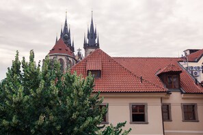 Un bâtiment avec un toit recouvert de tuiles rouges et une église avec plusieurs flèches en arrière-plan.