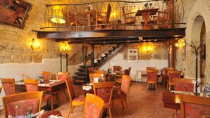 A restaurant with wooden furniture, stone walls, and a staircase leading to an upper level. - Tyn Yard Residence (Prague)