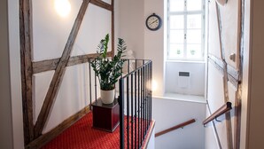 A staircase with exposed wooden beams, a potted plant, and a clock on the wall. - Tyn Yard Residence (Prague)