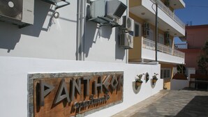 En byggnad med en skylt som visar texten ”PANTOKO Apartments”.