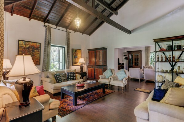 A spacious living room with high ceilings, wooden beams, and a variety of seating options including sofas and armchairs.