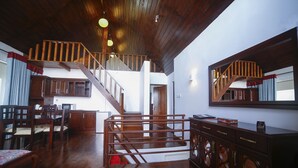 A spacious living area with a wooden staircase, a dining set, and a large cabinet with circular doors. - Blue Meadows - Nuwara Eliya (Nuwara Eliya)