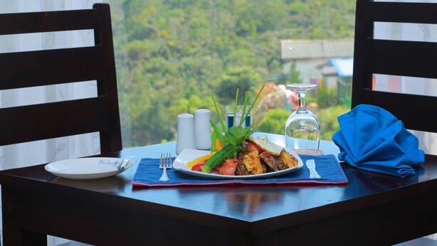 A dining table with a plate of food, salt and pepper shakers, a glass, and a blue napkin. - Blue Meadows - Nuwara Eliya (Nuwara Eliya)