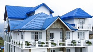 A multi-story building with a white exterior and blue roofs. It features balconies with railings and potted plants. - Blue Meadows - Nuwara Eliya (Nuwara Eliya)
