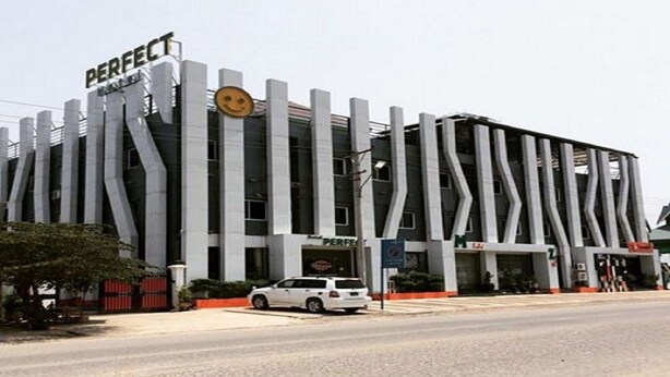 A building with a unique architectural design featuring vertical lines and the word "PERFECT" on the facade. - Perfect Hotel (Mandalay)