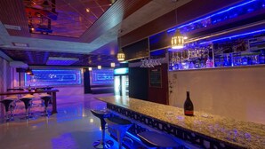 A bar area with a polished granite countertop, bar stools, and a bottle of wine. - Perfect Hotel (Mandalay)