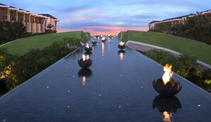 Un chemin bordé de lanternes en forme de lotus qui mène à un bâtiment au style architectural moderne.