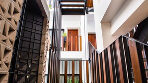 Un interior moderno con un muro de diseño geométrico, una escalera con barandillas de madera y vista a una puerta en la parte superior.