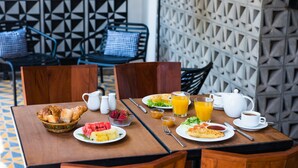 Una mesa de desayuno con croissants, fruta y zumo de naranja.