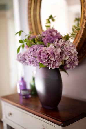 Un jarrón con flores moradas sobre un tocador de madera.