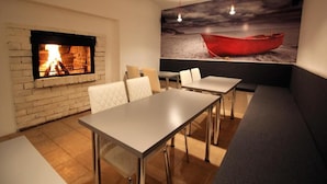 A cozy room with a fireplace, a dining table, and a bench. - Bed&Breakfast Baznicas 33 (Riga)