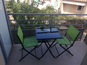Een klein balkon buiten met een tafel en twee stoelen.