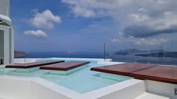 Una piscina al aire libre, sombrillas, sillones reclinables de piscina