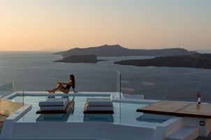 Una piscina al aire libre, sombrillas, sillones reclinables de piscina