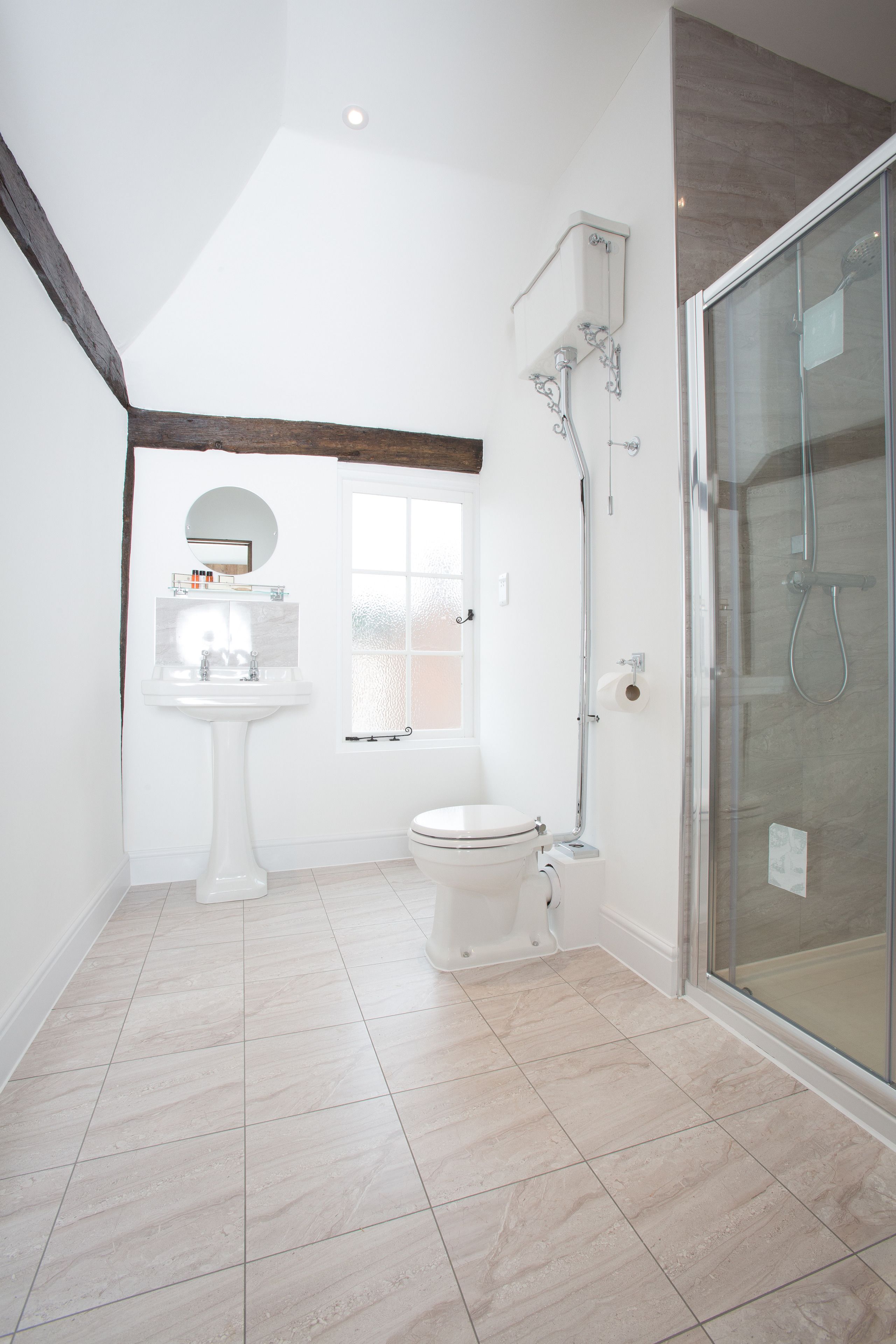 Un baño moderno con lavamanos pedestal, inodoro y cabina de ducha de vidrio.