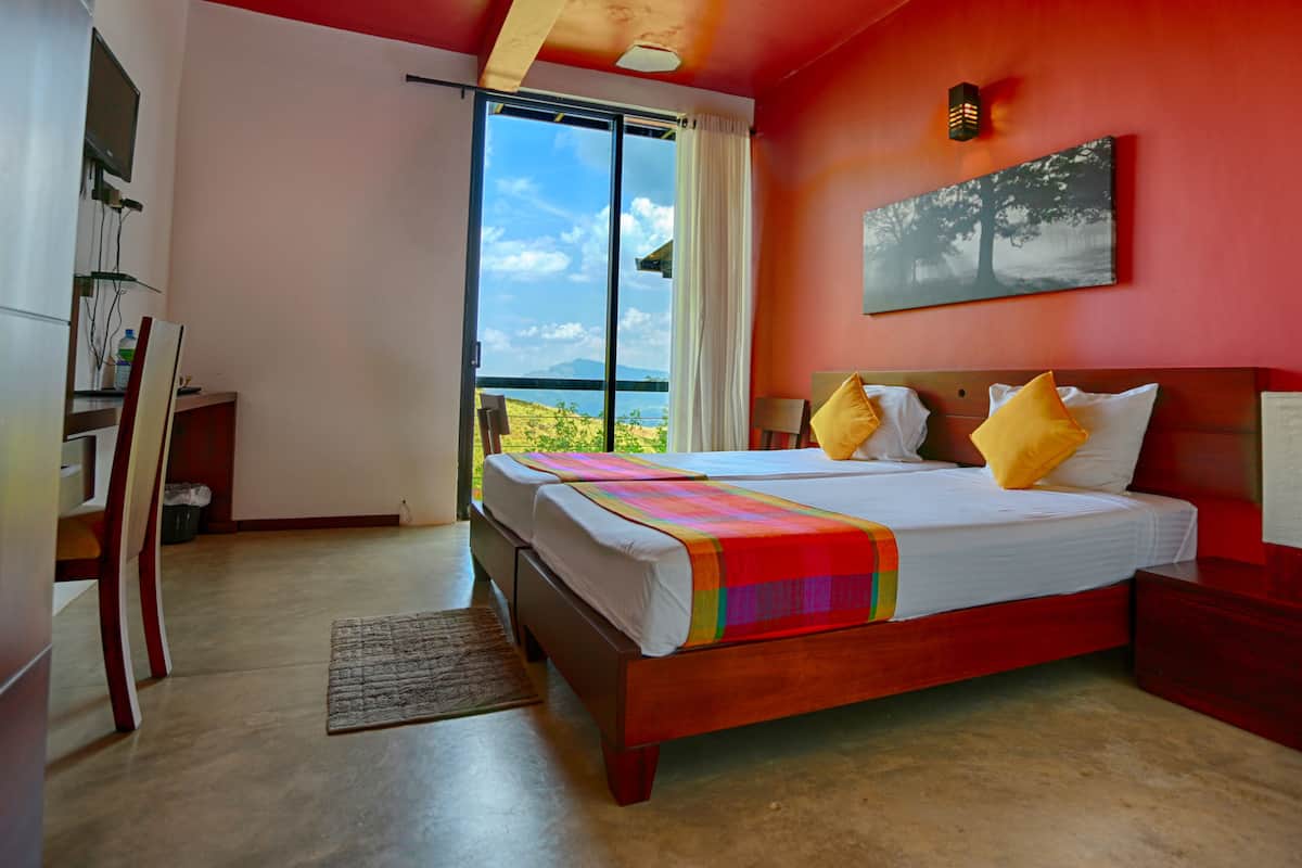 A bedroom with a large bed, a desk, and a window with a view of the outdoors.