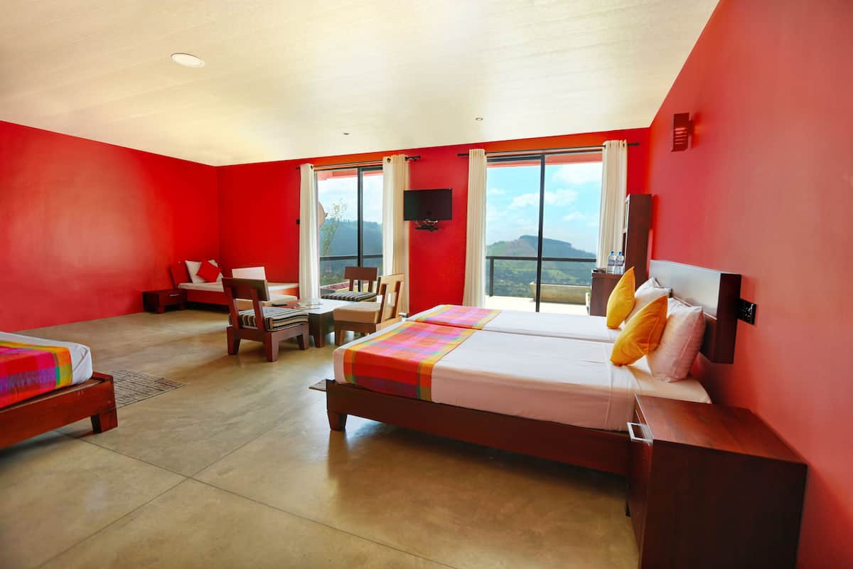 A hotel room with a large bed, a desk, and a chair. There is a window with a view of the mountains.