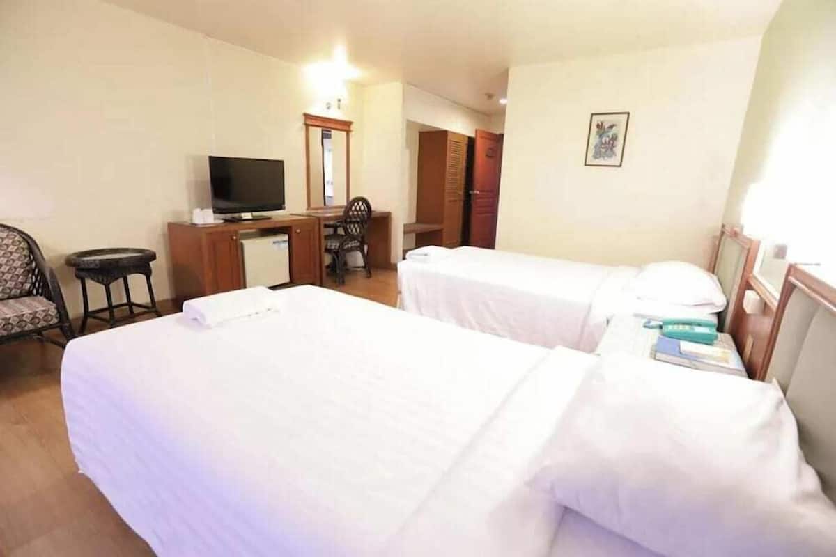 A hotel room with two beds, a desk with a TV, a chair, and a wardrobe.