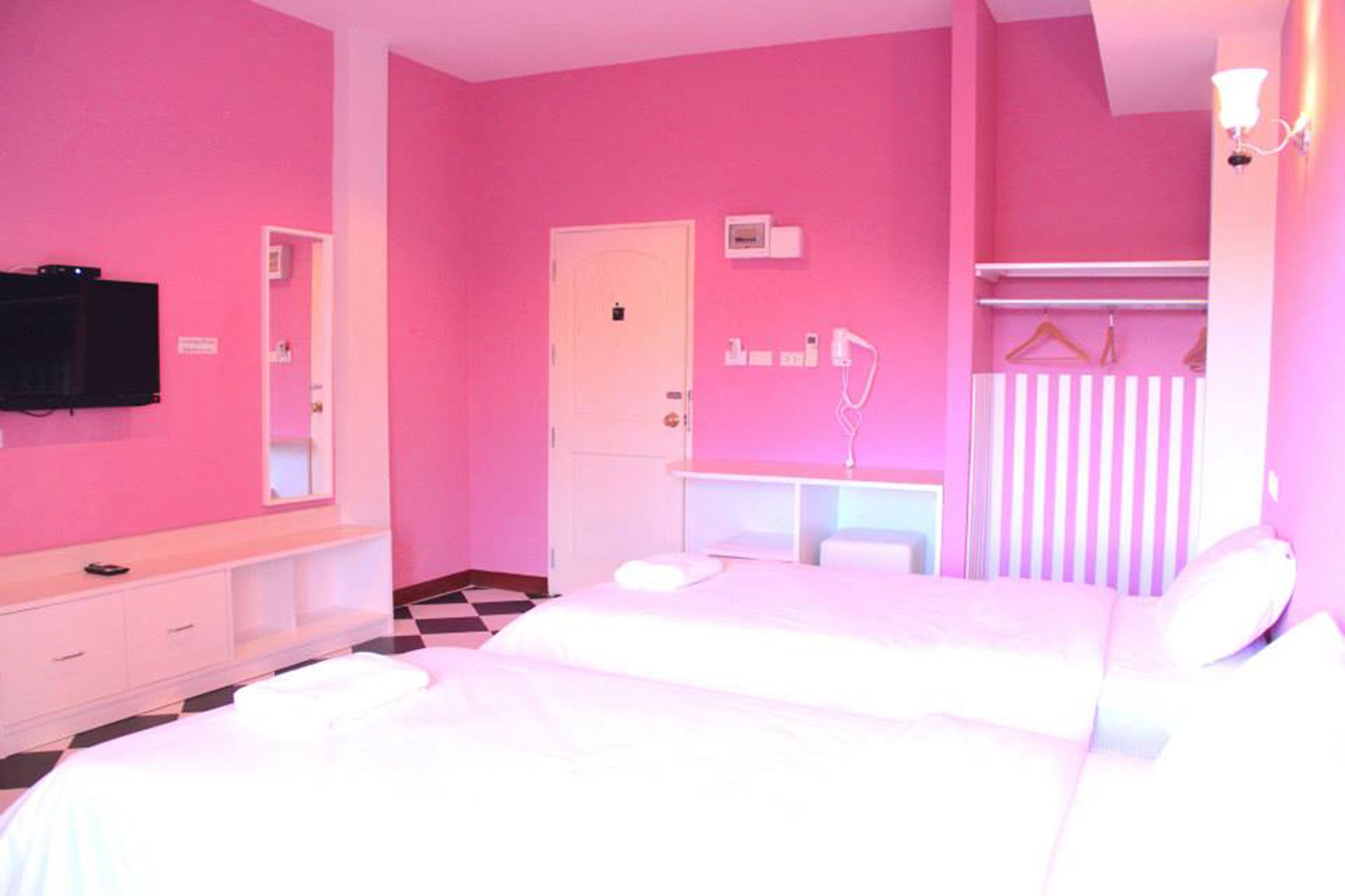 Une chambre à coucher décorée dans des tons roses, avec un lit, une table de chevet et un miroir.