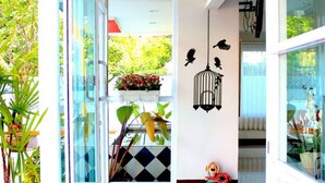 Un interior moderno con entrada de puerta de vidrio, suelo de baldosas y una jaula de pájaros decorativa.