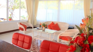 Habitación con sofá, dos sillones, una mesa de centro de vidrio y vistas al exterior.