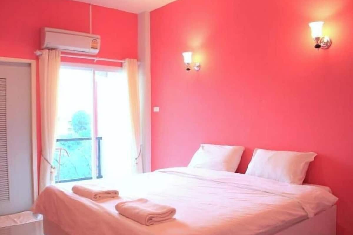 A room with a bed, two wall-mounted lights, an air conditioning unit, and a window with curtains.