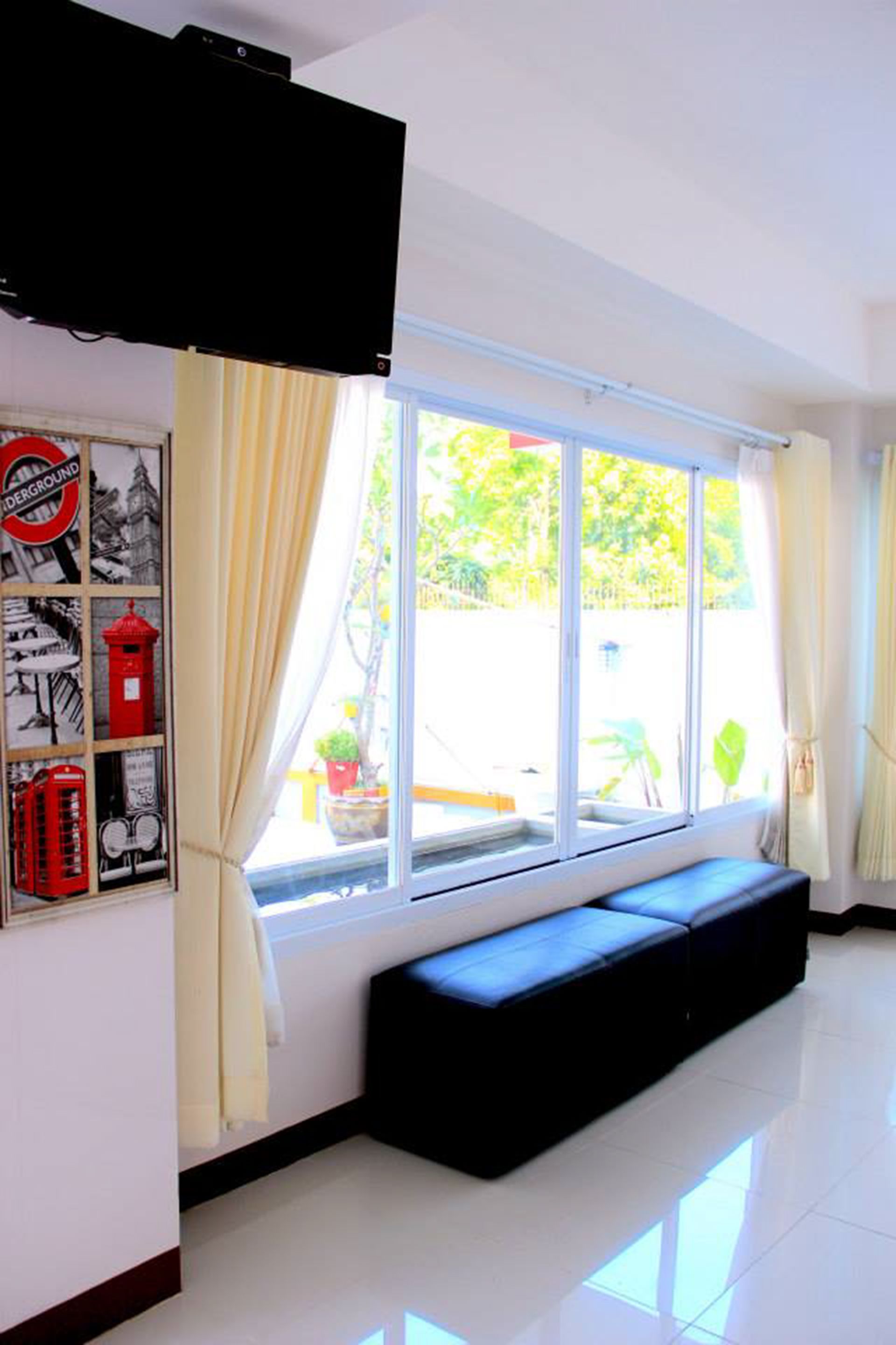 A room with a large window, a black bench, and a wall with various posters.