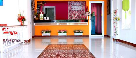 A reception area with a red wall, a reception desk, and a patterned rug.