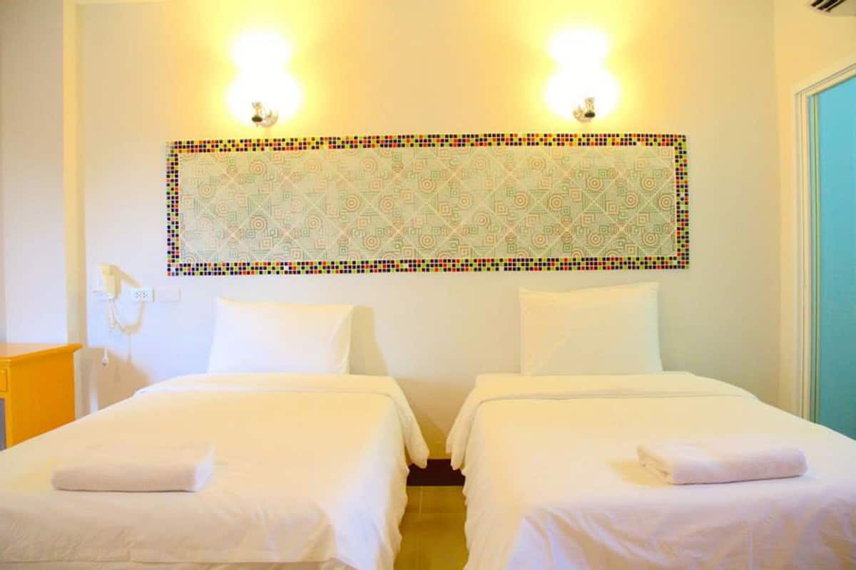 A hotel room with two beds, a wall-mounted light fixture, and a patterned wall decoration.
