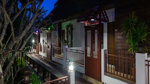 Una casa de madera tradicional con balcón, una puerta de madera y un pequeño jardín.