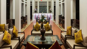 Un vestíbulo amplio con un área de estar central que incluye sofás y sillones, una mesa decorativa y vistas del interior del hotel.