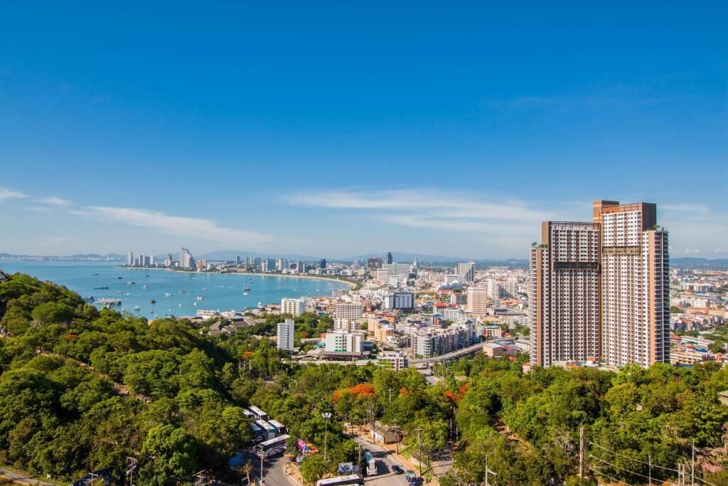 A coastal cityscape with a prominent high-rise building, dense urban area, and a bay with boats.