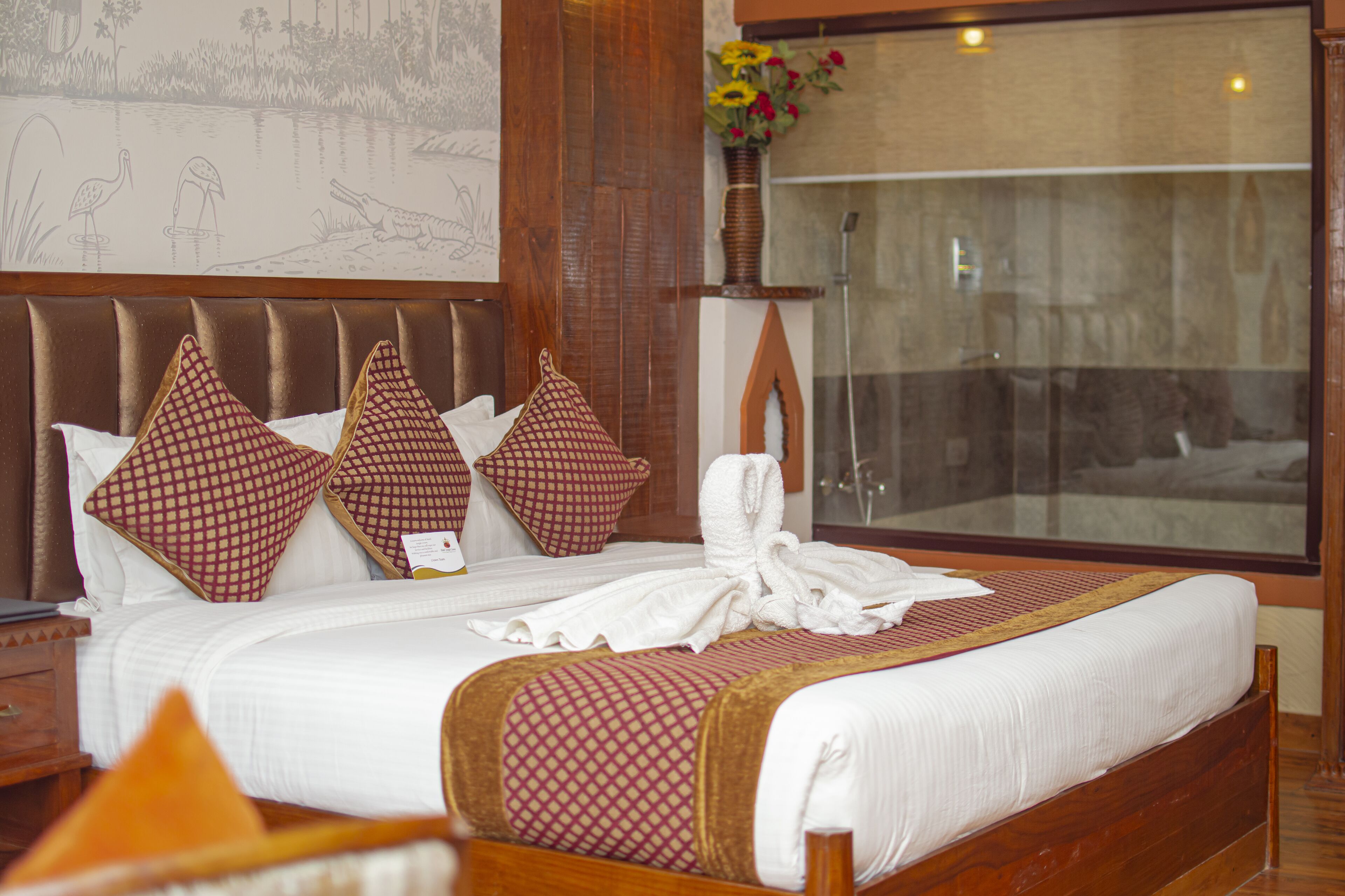 A hotel room with a large bed, wooden headboard, and a mural on the wall.