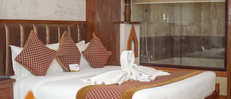 A hotel room with a large bed, wooden headboard, and a mural on the wall.