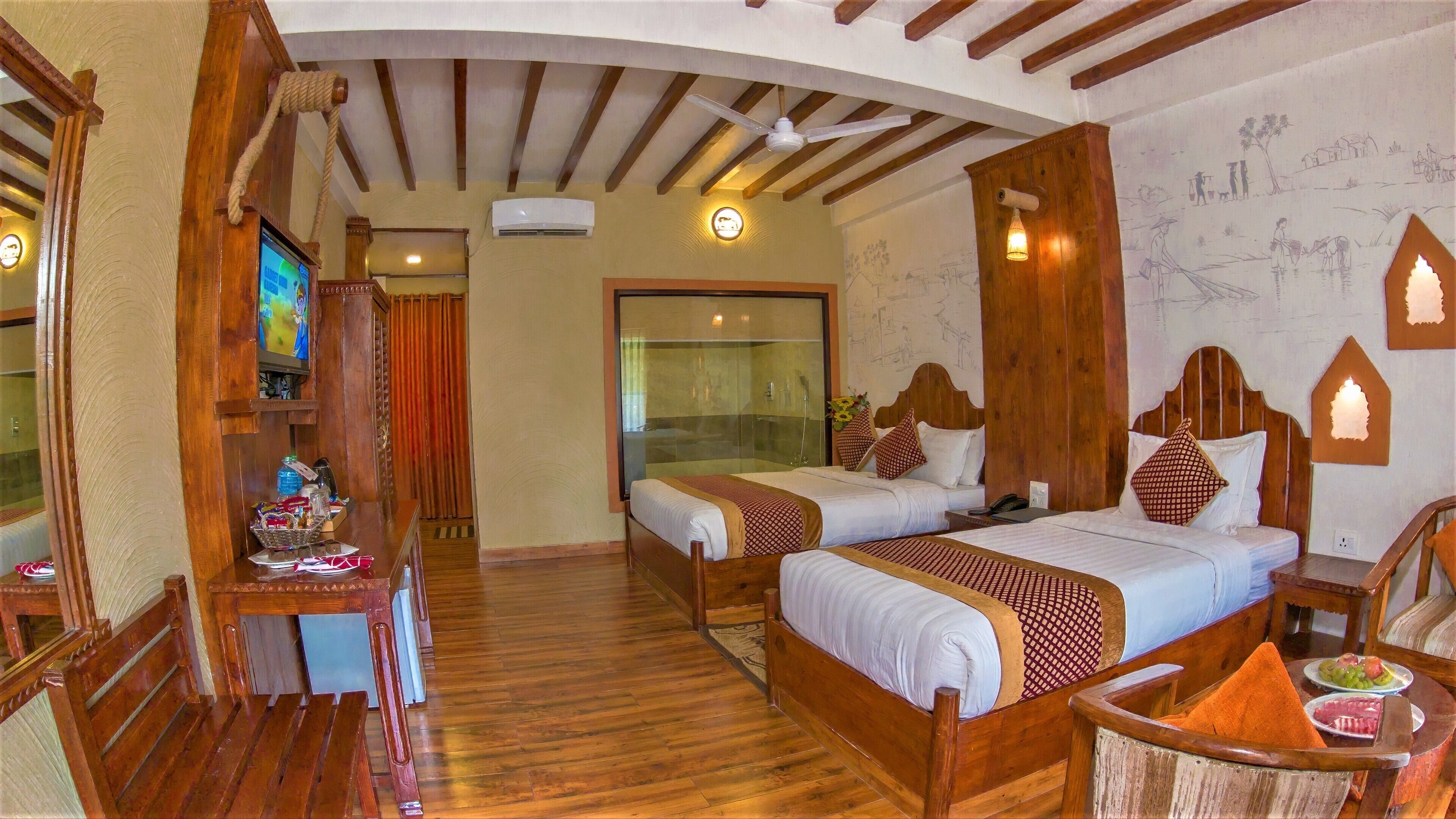 Une chambre d’hôtel avec deux lits en bois, un bureau en bois avec une télévision et une salle de bain avec une douche en verre.
