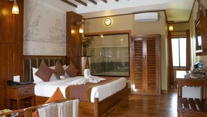 Um quarto espaçoso com uma cama grande, cabeceira de madeira e uma mesa de cabeceira.